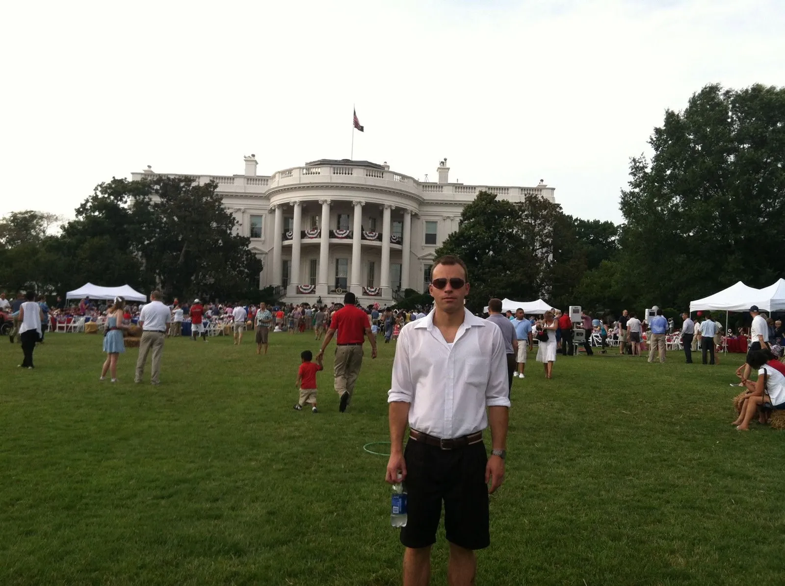 Oliver standing on the South Lawn at an outdoor event, the White House behind him.